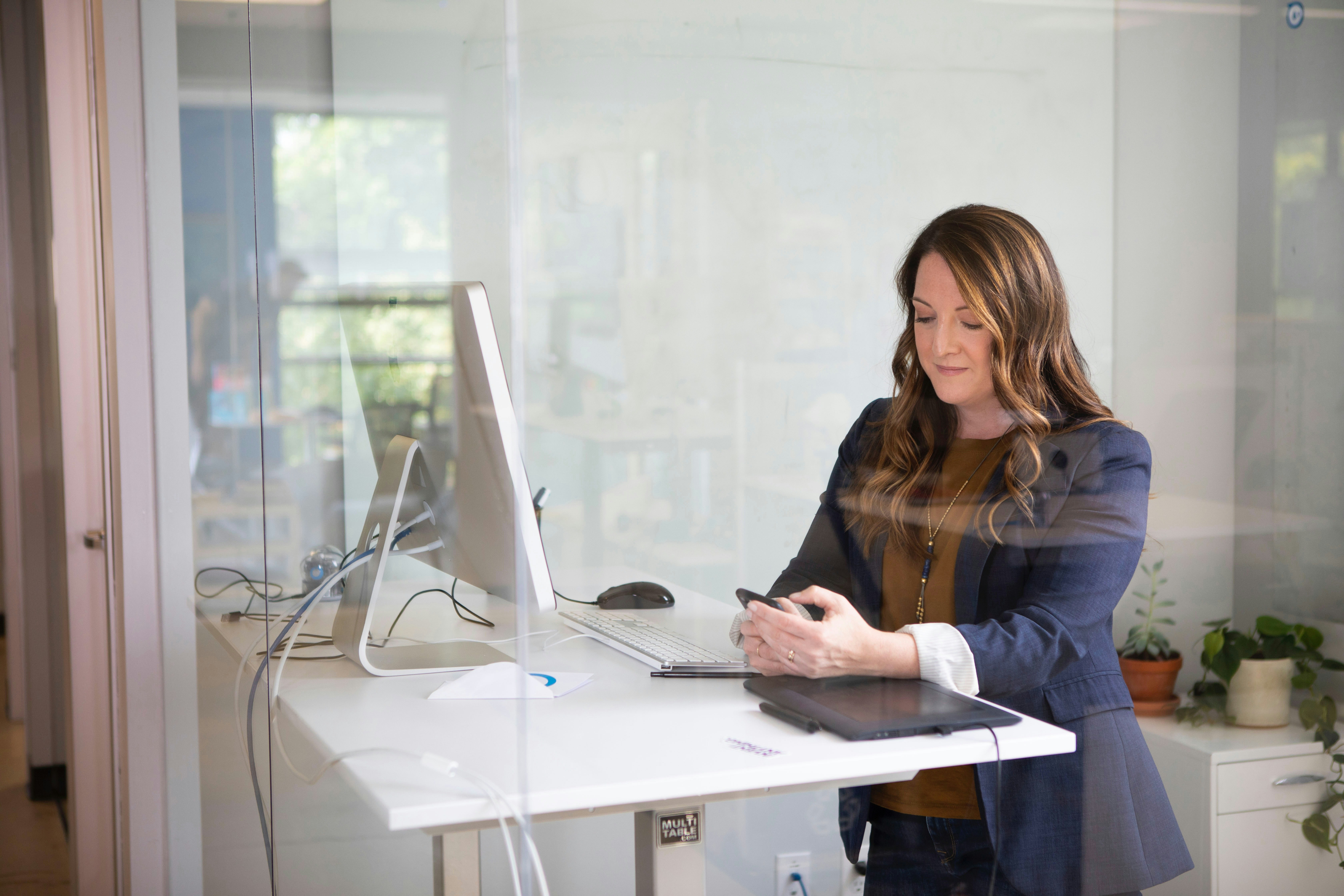 A woman working at a desk with a notebook and laptop